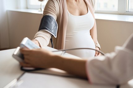 A pregnant person has their blood pressure read by an arm cuff.