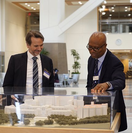 Aiyelawo places hand on case over the CC model, talking with Plescia in CC atrium