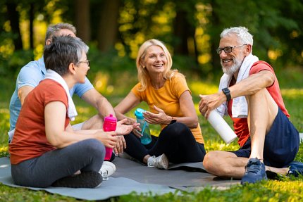 A group of older adults sit on the ground with water bottles in their hands