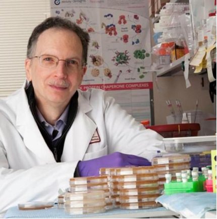 Neckers in lab coat at table with lab equipment