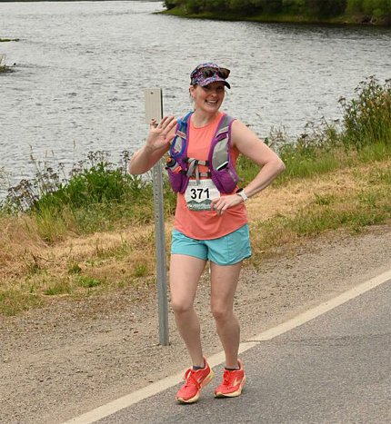 Roth waves as she runs along the side of a rode bordered by a body of water