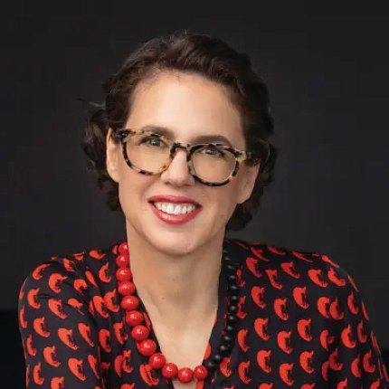 Headshot of Gallo, wearing a red a black patterned shirt and coordinating necklace.