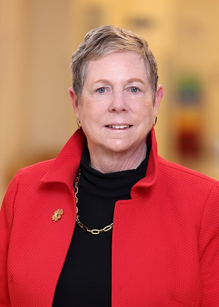 Headshot of Jaffe, wearing a black shirt and red jacket, against a blurred background.