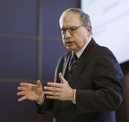 Tabak standing, talking, holding out his hands