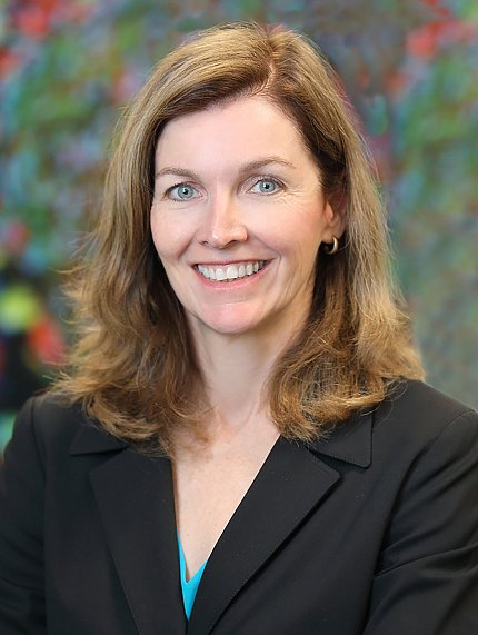 Headshot of a smiling McGowan, who is silhouetted against a blurry floral background.