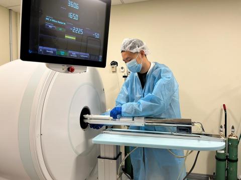 A scientist in scrubs stands by PET scanner