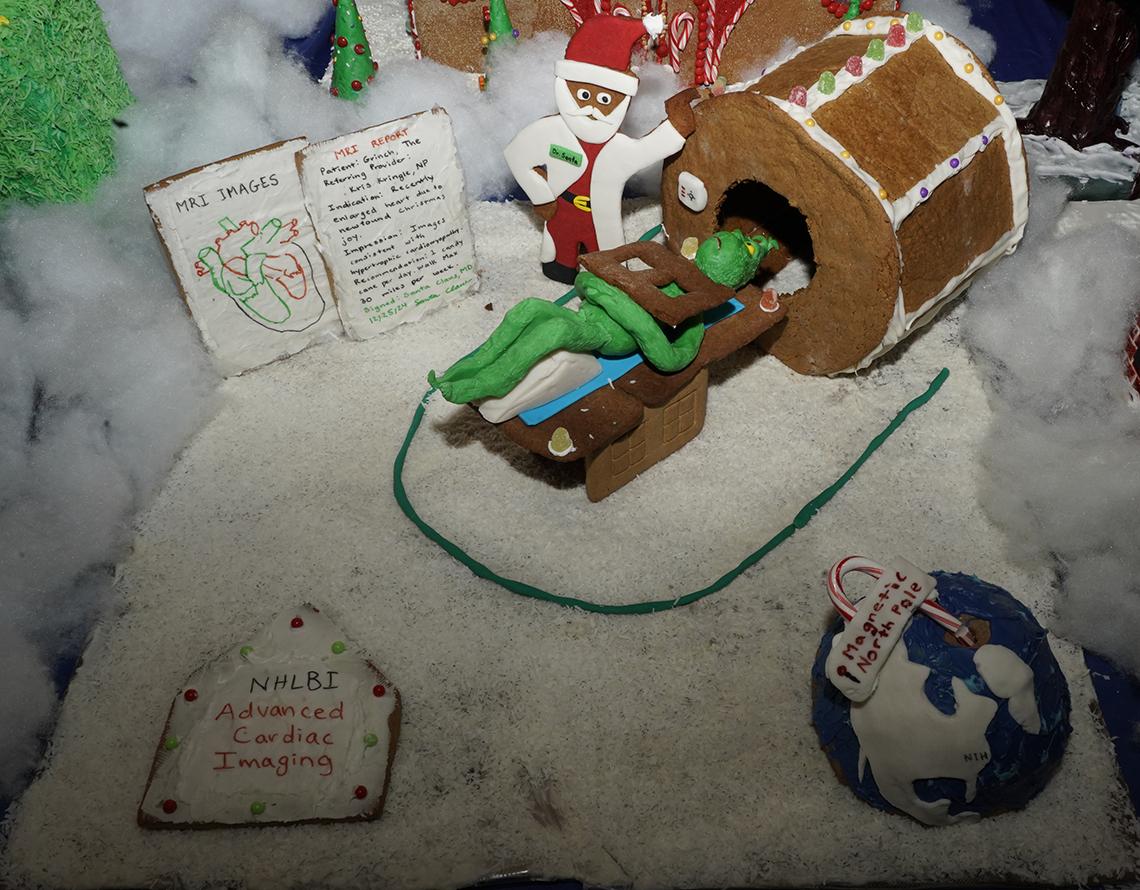 A gingerbread of the grinch laying down, entering an MRI scanner, with Dr. Santa at his side