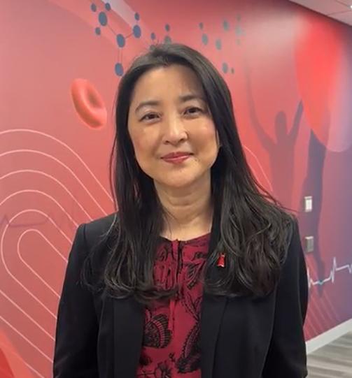 Wei in red shirt and blazer in front of pink backdrop