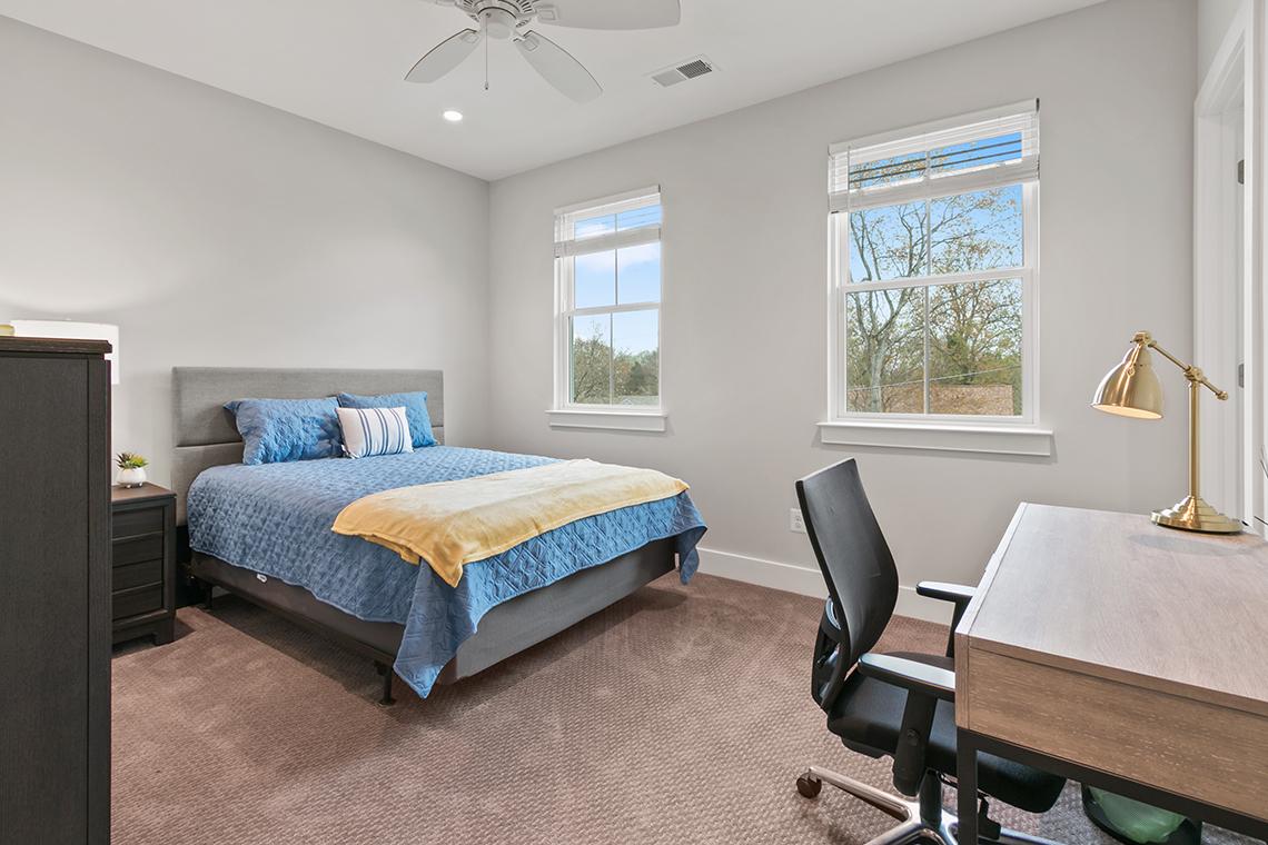 An interior view of a bedroom with a desk and chair