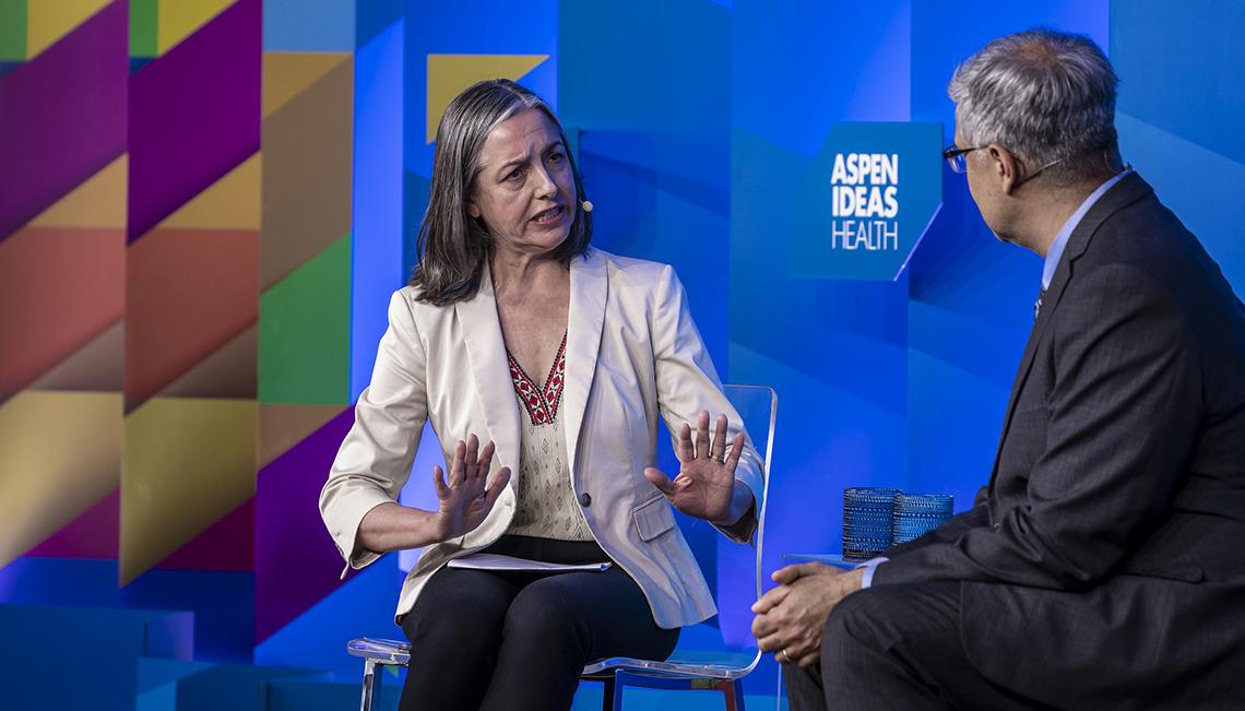 Reporter with palms up talks with Bhattacharya on stage