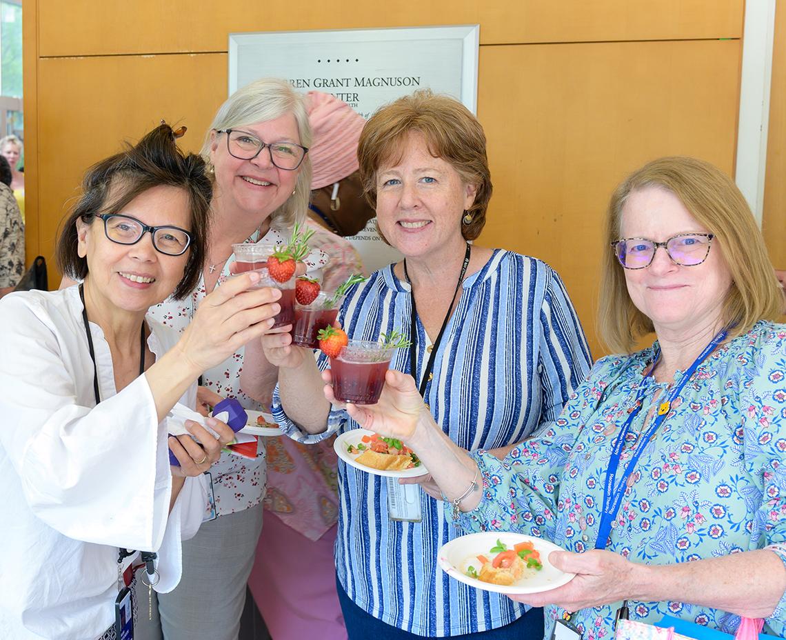 Four women toast with their red, fruity drinks.