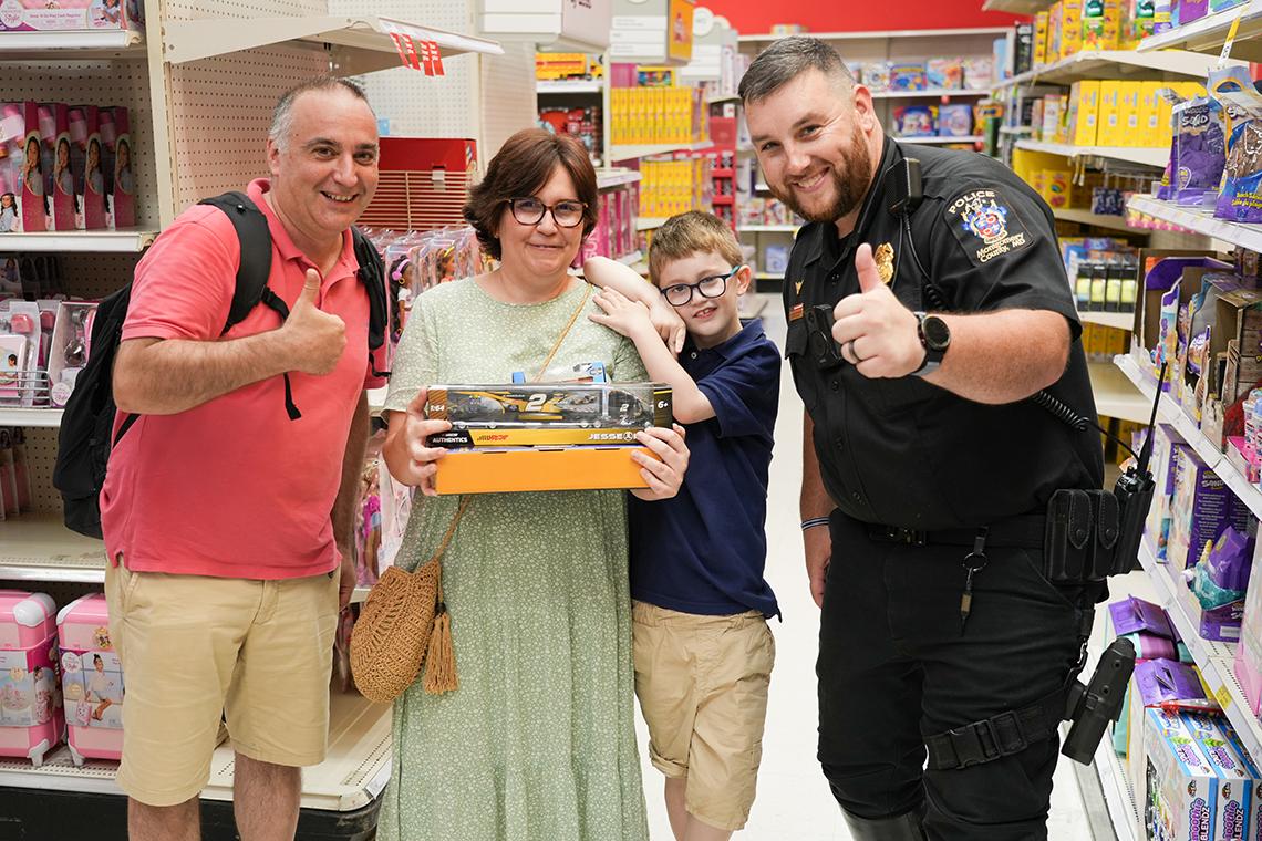 A son and his parents in the aisle at Target hold up a toy next to a cop