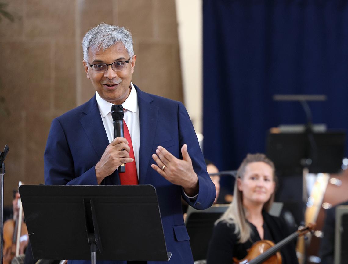Bhattacharya, hand to chest, smiles as he speaks into mic.