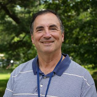 Basser smiling outside, with trees behind