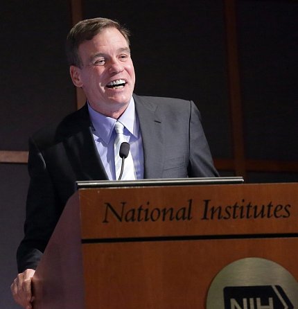 Sen. Warner smiles at podium. Sen. Warner smiles at podium.