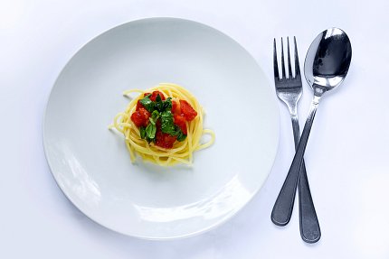 Spaghetti Spaghetti and red sauce on a white plate next to silverware