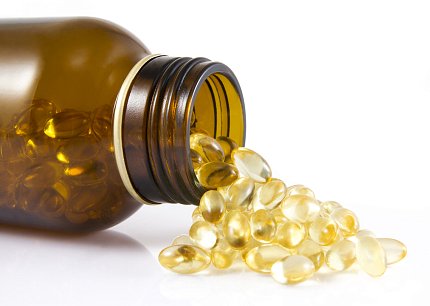 Bottle of vitamins A medicine bottle lies on its side with pills spilling on the table