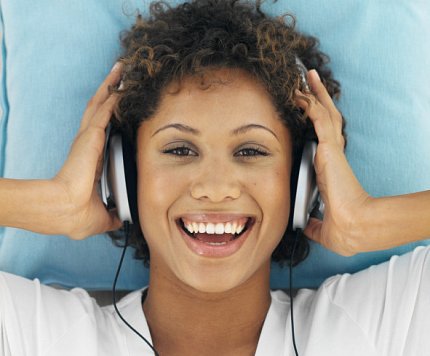 A woman listens to music A smiling woman listens to music through headphones.