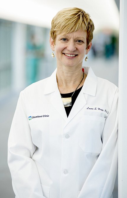 Dr. Laura E. Nagy Nagy stands, smiling, in a white lab coat.