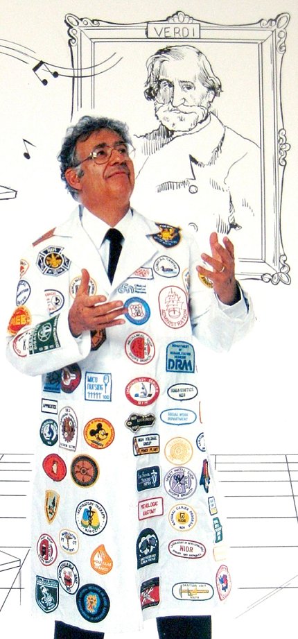 Dr. Saul Rosen Rosen wears a lab coat with logos while standing in front of a cartoon portrait of Verdi
